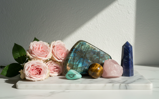 Labradorite, tiger's eye, amazonite, rose quartz and sodalite crystals on white marble with soft pink roses — crystals for reassurance seeking and self-trust by Heavenly Crystals Online.