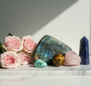 Labradorite, tiger's eye, amazonite, rose quartz and sodalite crystals on white marble with soft pink roses — crystals for reassurance seeking and self-trust by Heavenly Crystals Online.