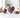 Rhodonite heart, sphere and palm stone with pink and black veining, arranged with soft pink roses on white marble.