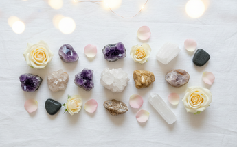 Natural raw stones and healing crystals arranged with roses and fairy lights