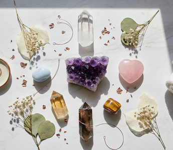 Luxury flat lay of 7 healing crystals for beginners including clear quartz, amethyst, rose quartz, citrine and smoky quartz on white marble