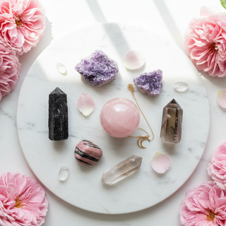 Black tourmaline, lepidolite, rose quartz, rhodonite and smoky quartz crystals on white marble with soft pink roses — healing crystals for Complex PTSD support by Heavenly Crystals Online.