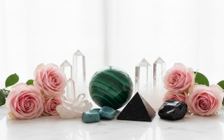Malachite, clear quartz, shungite, amazonite and obsidian crystals on white marble with soft pink roses — healing crystals for somatic pain support by Heavenly Crystals Online