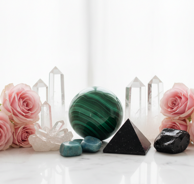 Malachite, clear quartz, shungite, amazonite and obsidian crystals on white marble with soft pink roses — healing crystals for somatic pain support by Heavenly Crystals Online