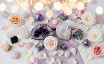 Crystal clusters, geodes, bismuth and natural raw stones arranged with roses and fairy lights